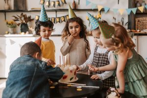 Children celebrate a birthday and eat cake.